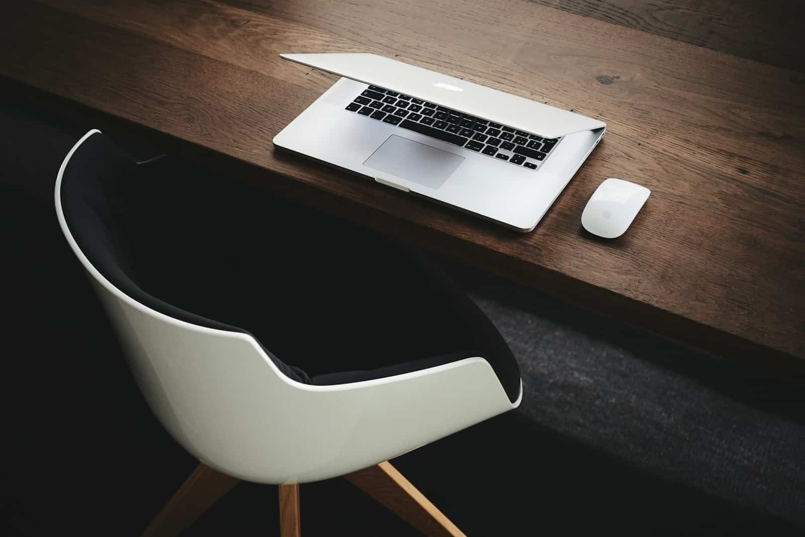 Laptop and mouse on a wooden desk in a modern workspace