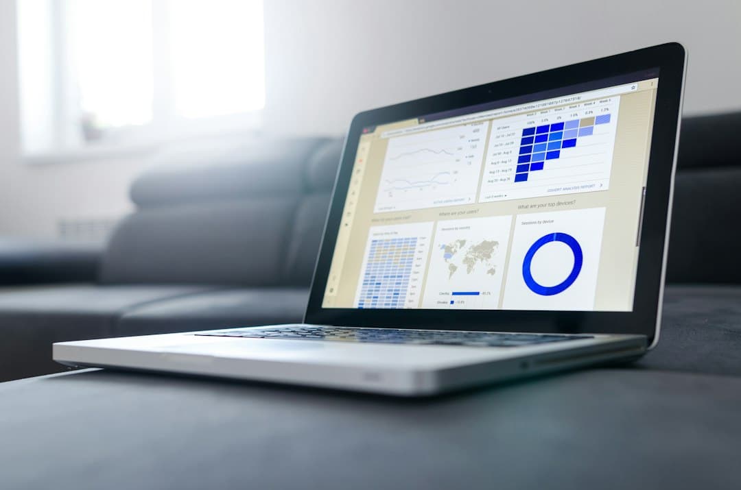 Laptop displaying business data beside a notebook, representing connected website systems